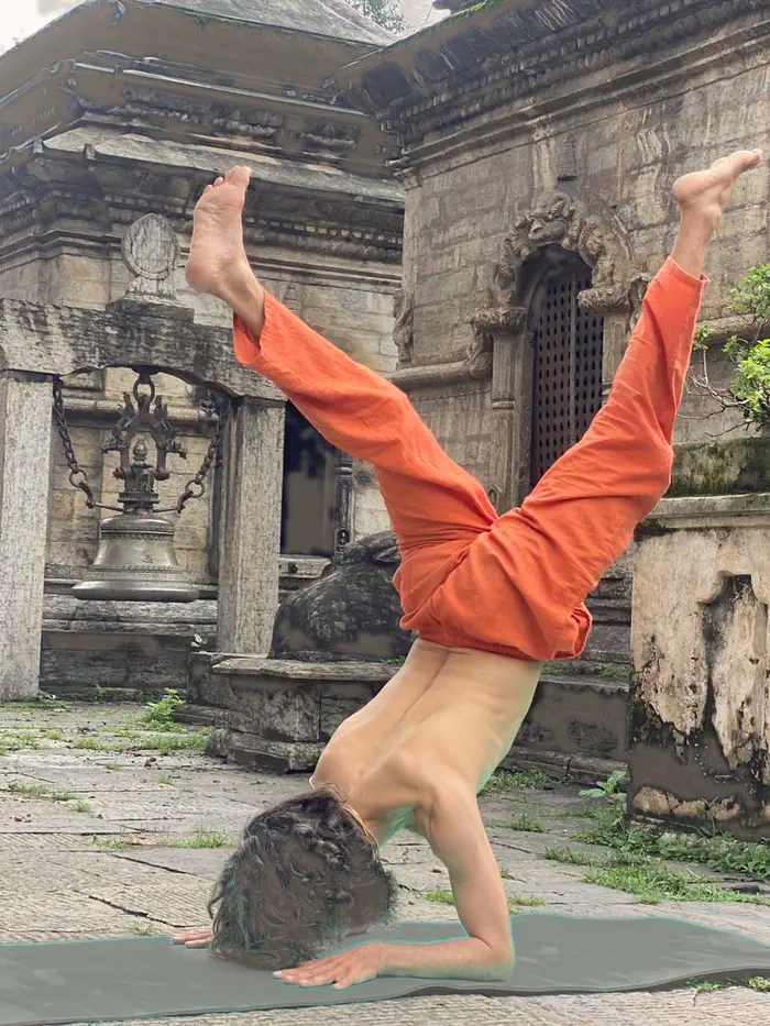 Yogi Ji inverted in a headstand beside the carved stone shrines of the temple complex.