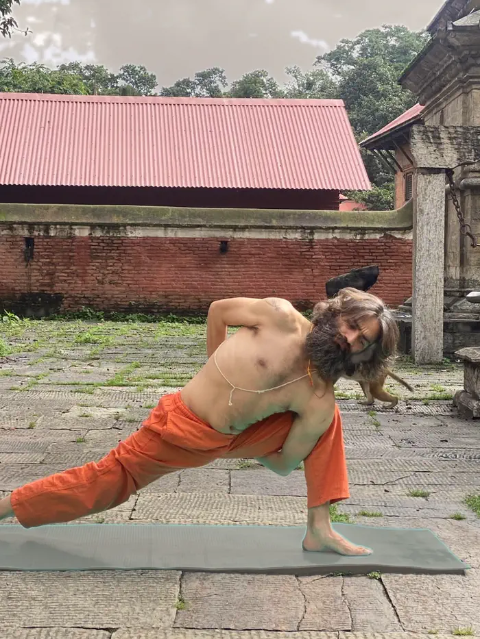 Yogi Ji in a deep side stretch on the worn stone of the temple courtyard.